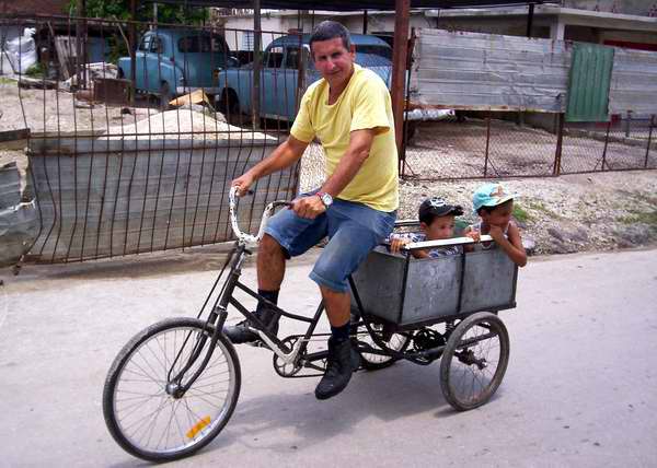 Papá paseando a sus dos pequeños en triciclo Papá paseando a sus dos pequeños en triciclo
