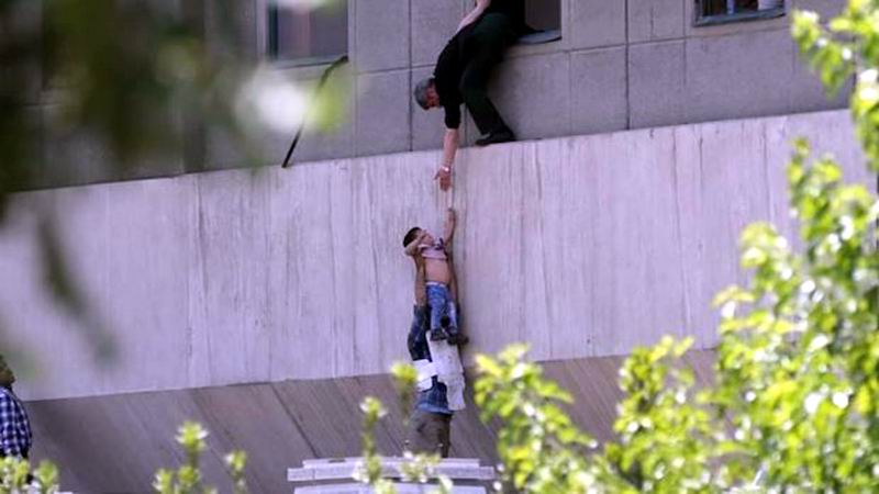 Un policía iraní evacua a un niño del edificio del parlamento atacado por terroristas. Foto: AFP
