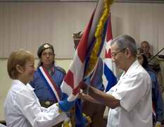 Jos&eacute; Ram&oacute;n Balaguer, ministro de Salud, entrega la bandera a Sara Lidia Romero durante la despedida de la brigada m&eacute;dica que parte hacia Ecuador 
